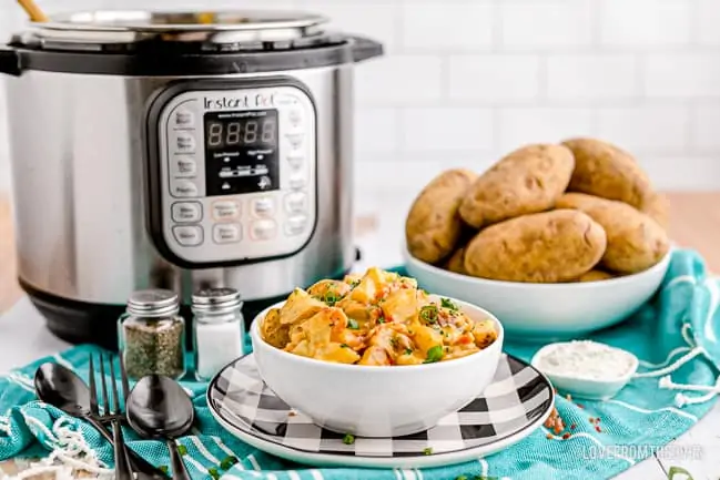 A bowl of cheesy potatoes in front of an instant pot
