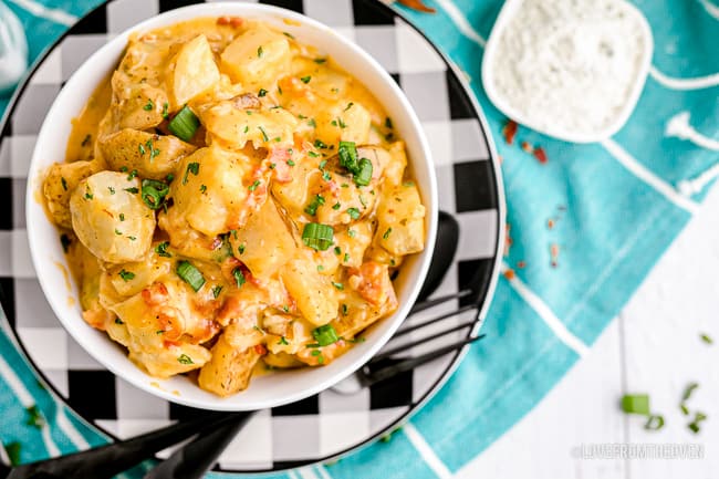 A bowl of cheesy ranch potatoes on a black and white plate