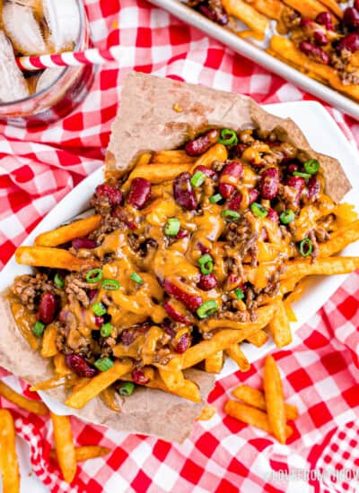 a basket of chili cheese fries on a red and white tablecloth