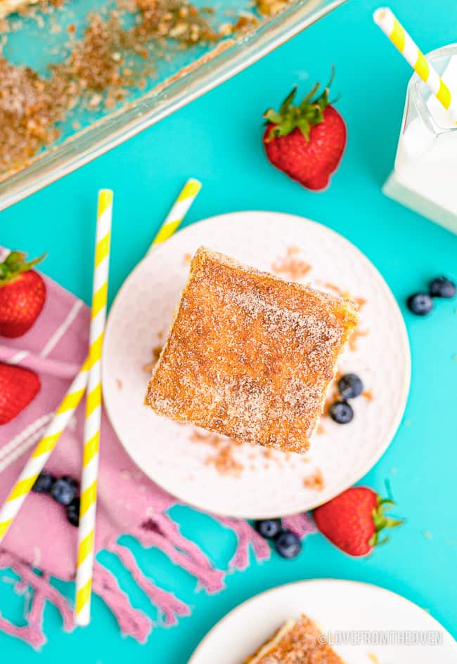 a plate of churro cheesecake bars on a blue background