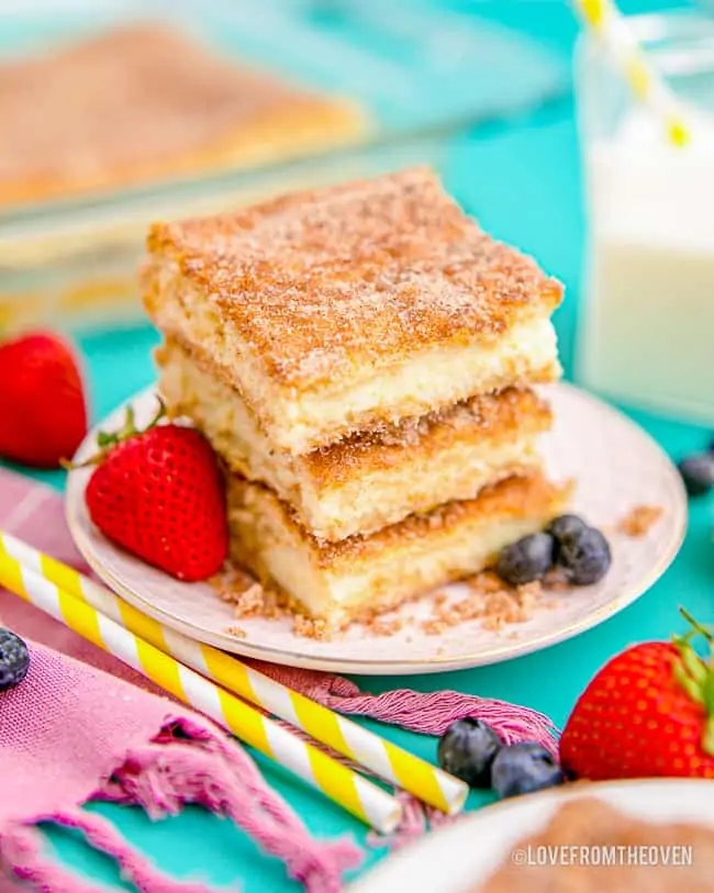 a stack of cheesecake bars topped with cinnamon and sugar