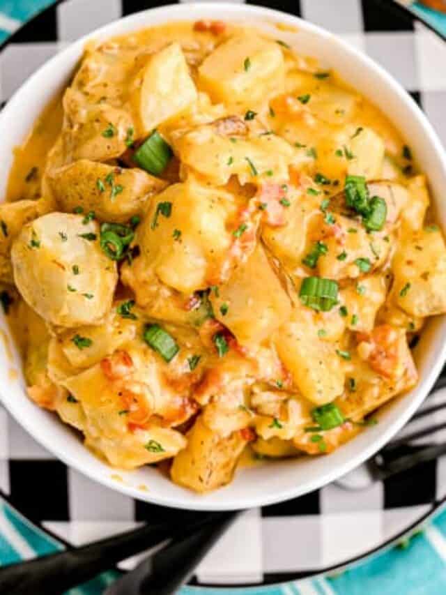 A bowl of cheesy ranch potatoes on a black and white plate