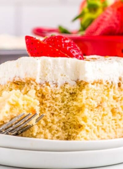 a slice of tres leches cake with a red container behind it