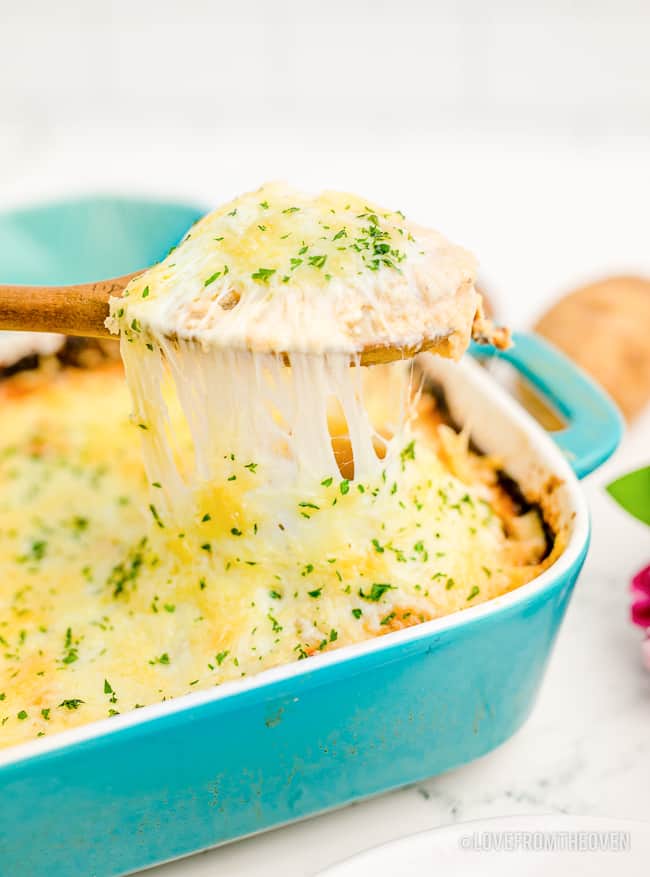 a spoonful of scalloped potatoes being taken from a pan