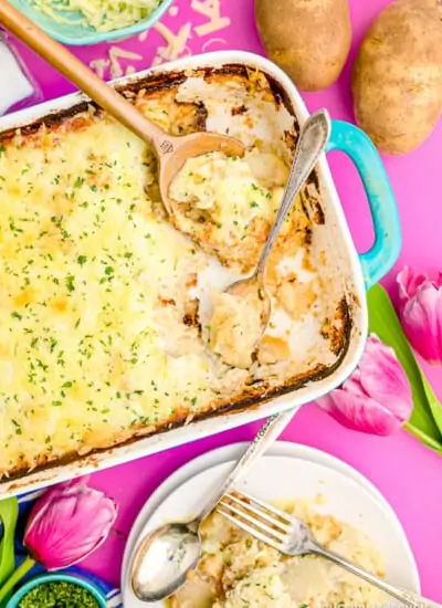 A pan of scalloped potatoes on a pink background