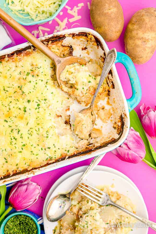 A pan of scalloped potatoes on a pink background