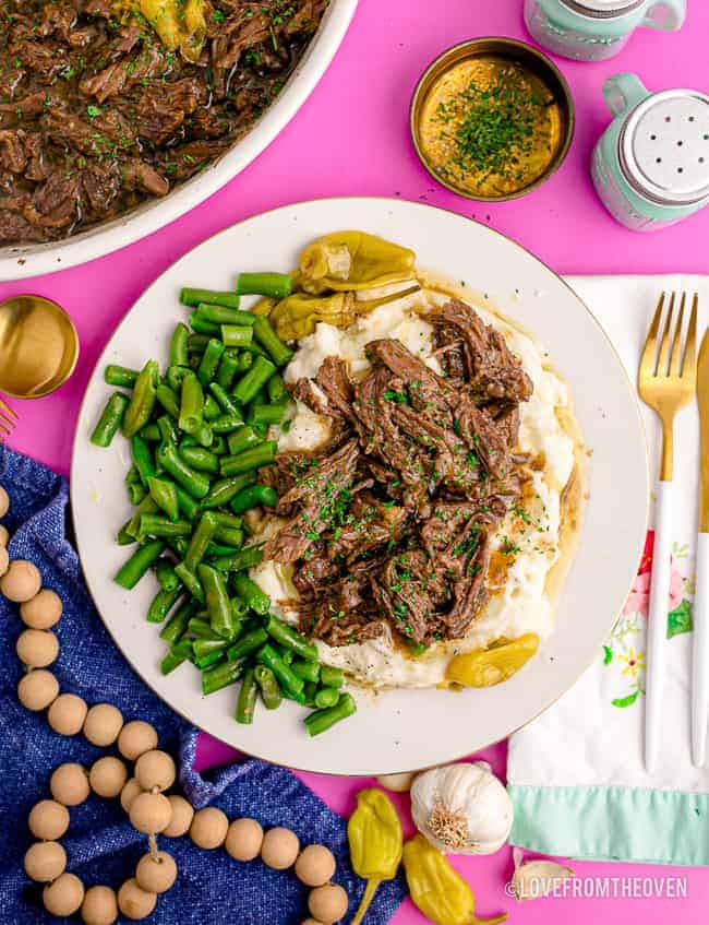 a plate with Mississippi pot roast, potatoes and green beans