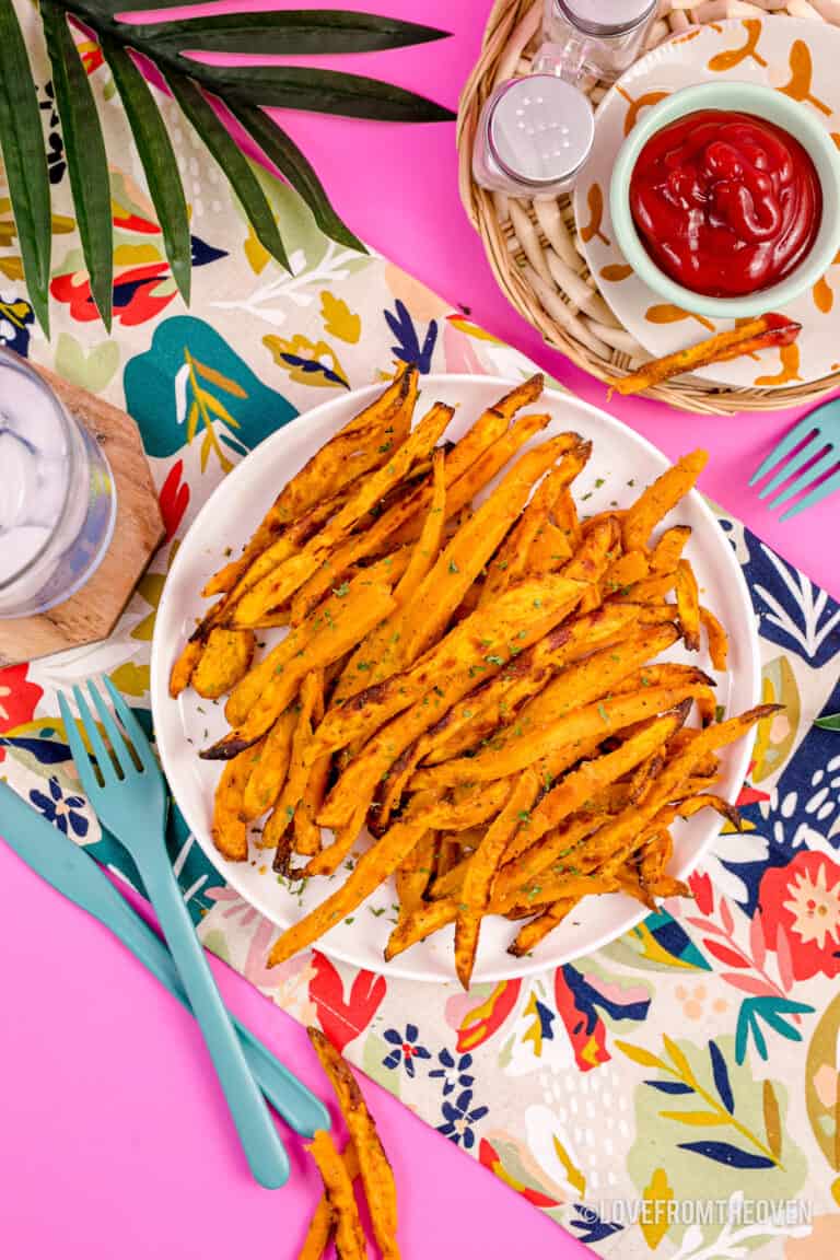 A plate of air fryer sweet potato fries on a pink background.