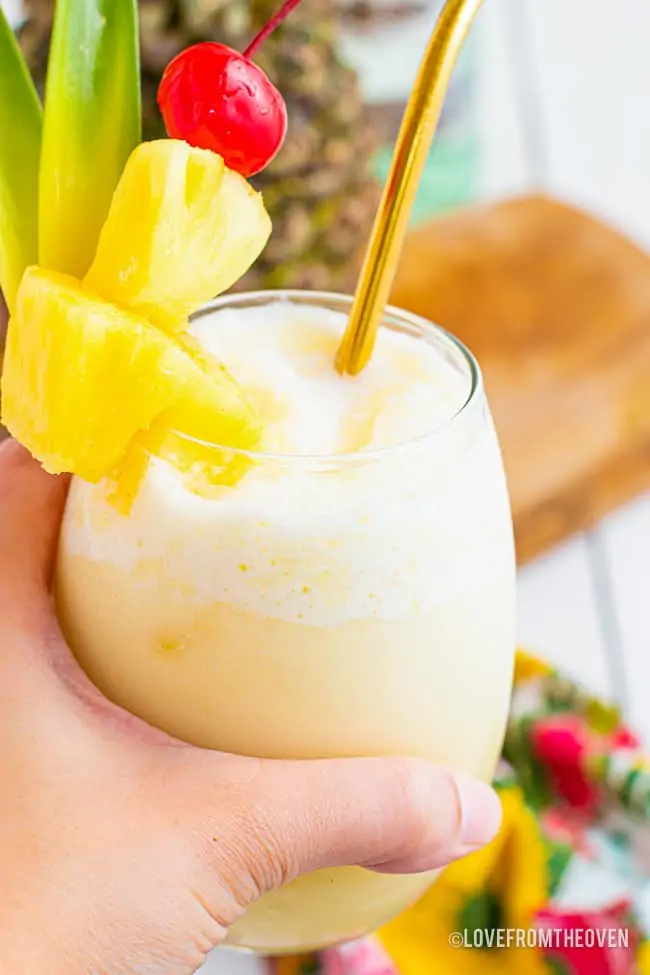 A hand holding a glass of pina colada.