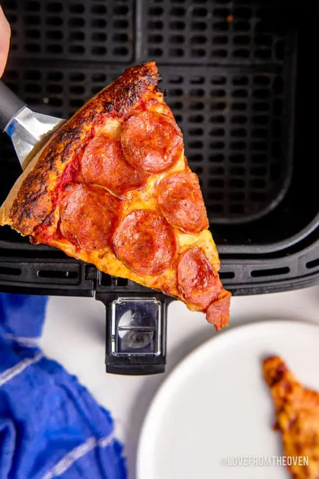 A slice of pizza in an air fryer.
