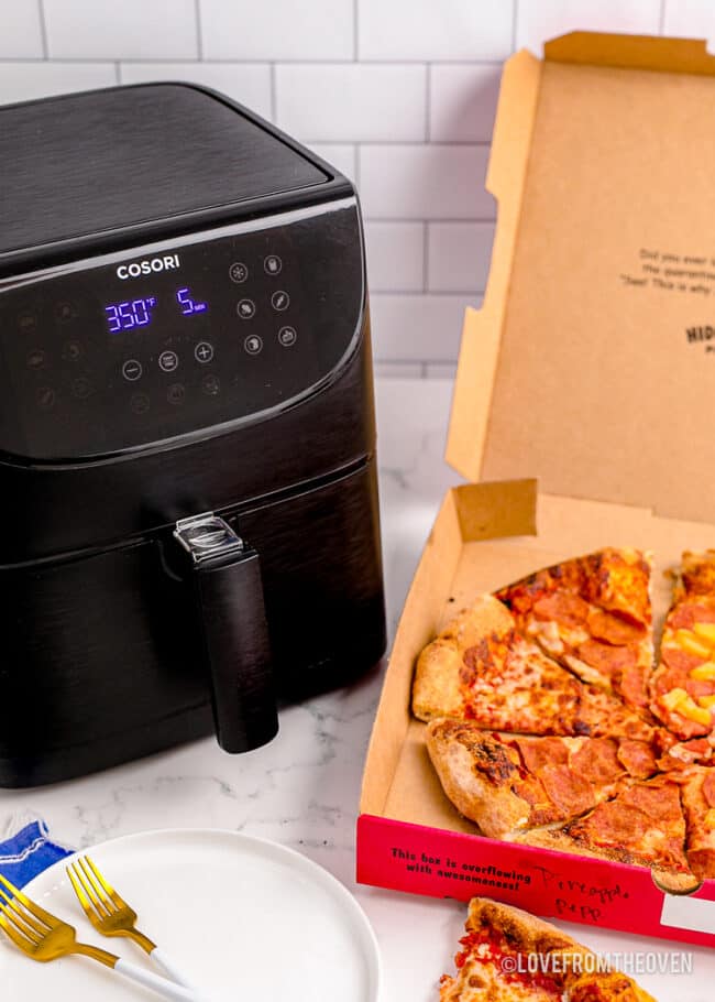 An air fryer and a box of pizza to be reheated.