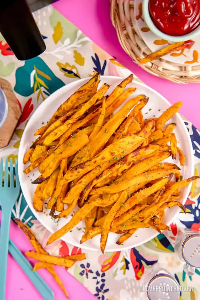 A plate of sweet potato fries on a pink background.
