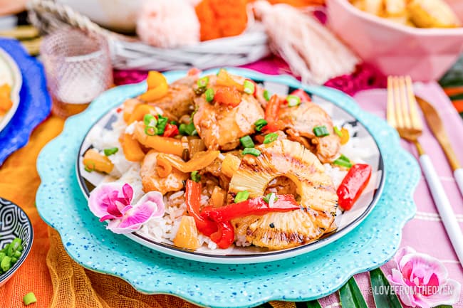 A plate of Hawaiian chicken with a colorful background.