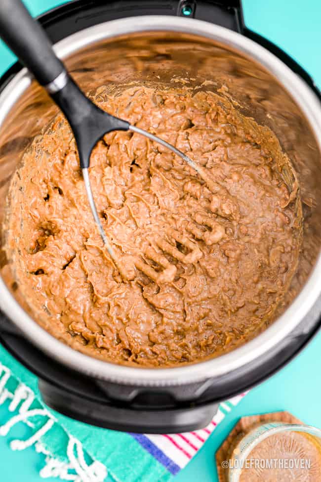 Refried beans in an instant pot being mashed.