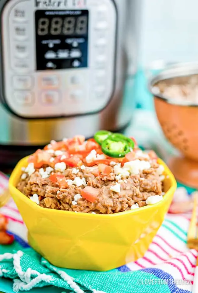 A bowl of homemade refried beans in front of an Instant pot.