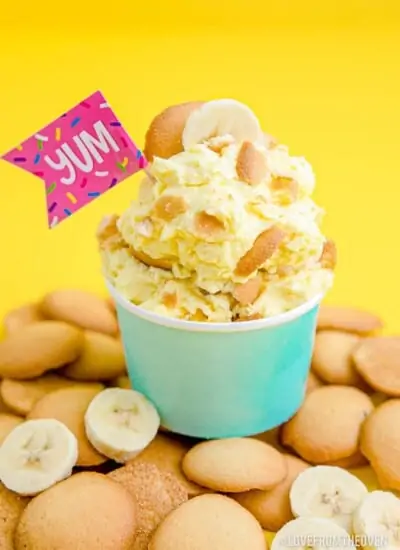 A cup of Magnolia Bakery Banana Pudding on a pile of vanilla wafer cookies.