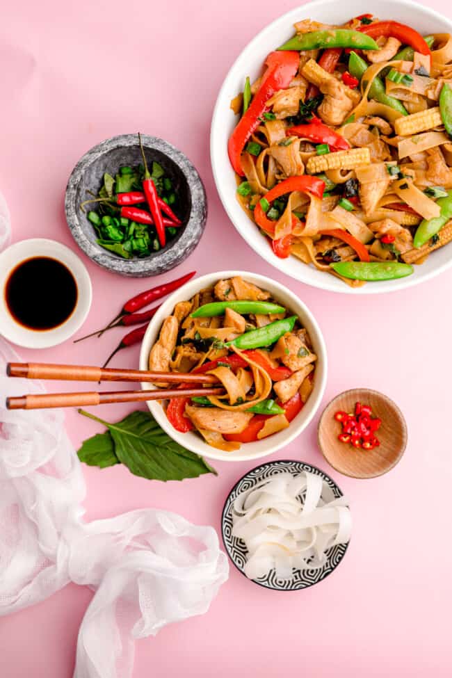 Photos of Thai drunken noodles on a pink background.