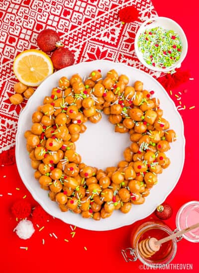 Struffoli on a white plate with a red background.
