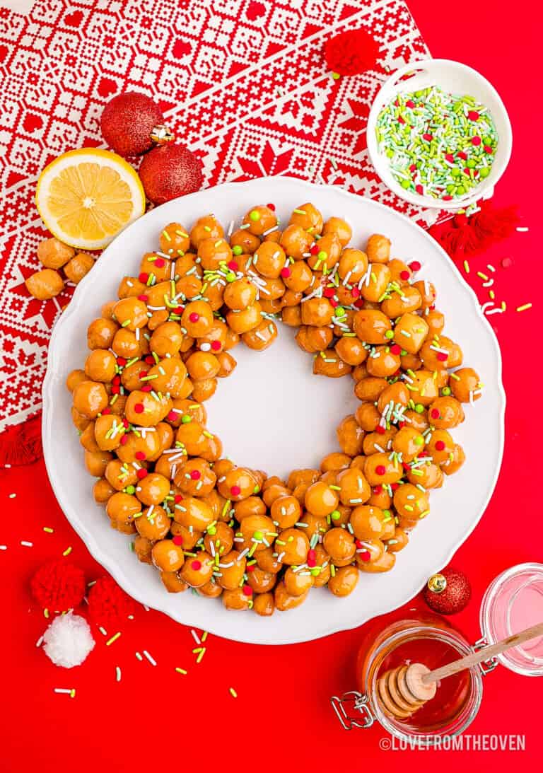 Struffoli on a white plate with a red background.