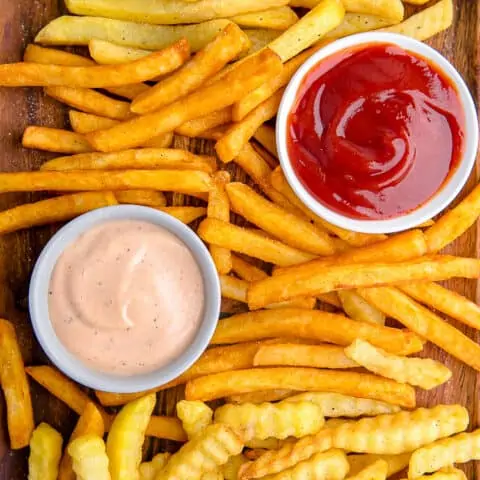 French fries on a baking sheet with dipping sauces.