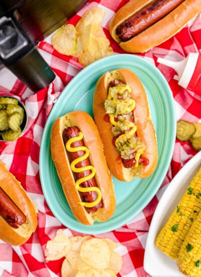 Two hot dogs in front of an air fryer.