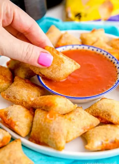 An air fryer pizza roll being dipped in tomato sauce.