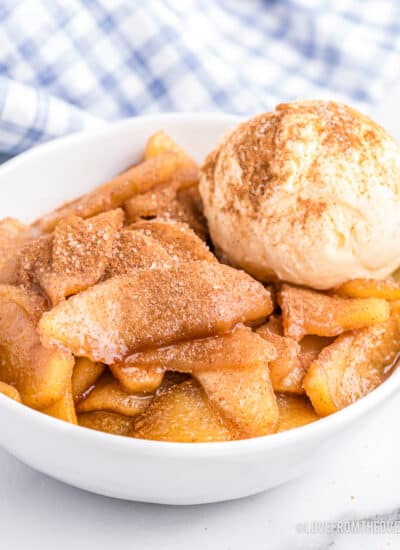 A bowl of baked cinnamon apples with a scoop of ice cream.