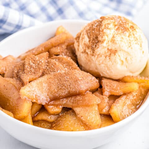 A bowl of baked cinnamon apples with a scoop of ice cream.