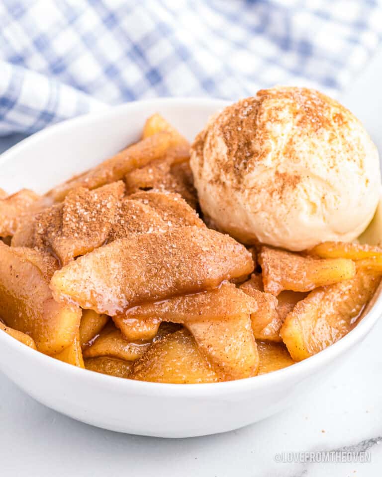 A bowl of baked cinnamon apples with a scoop of ice cream.