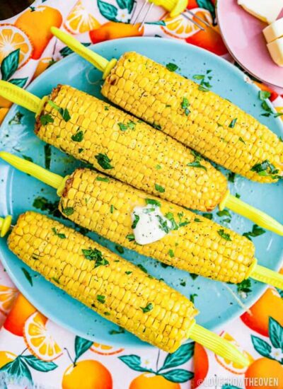 Cooked corn on the cob ears on a blue plate.