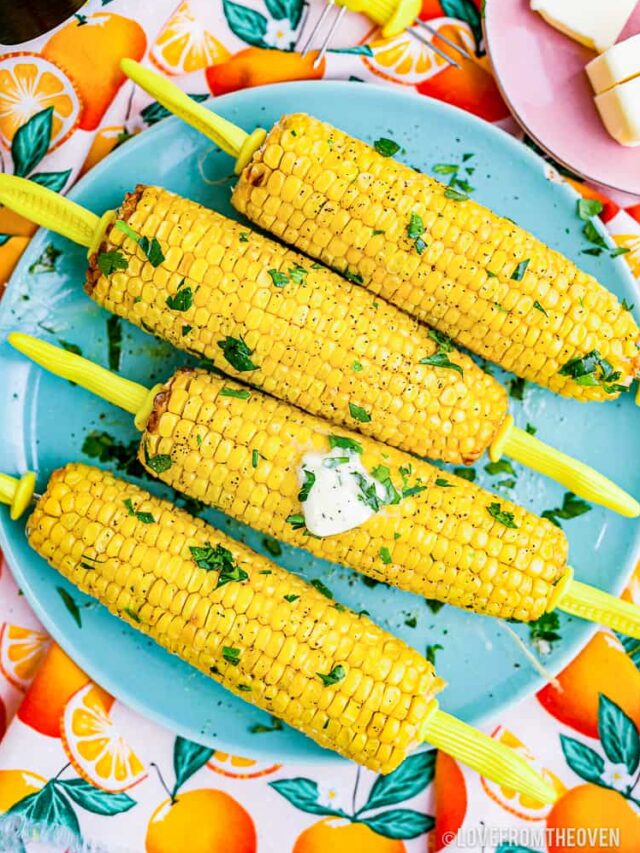 Cooked corn on the cob ears on a blue plate.