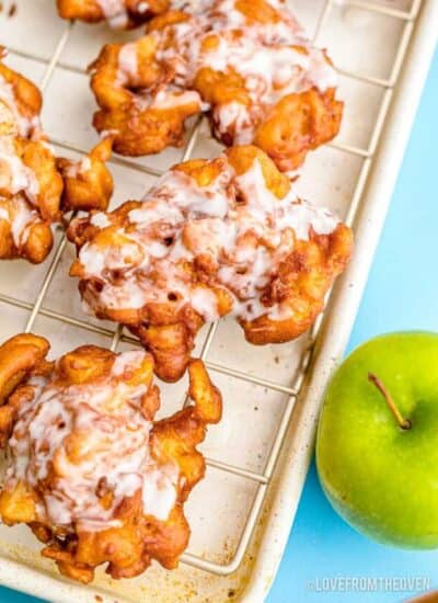 apple fritters on a cooling tray next to a green apple