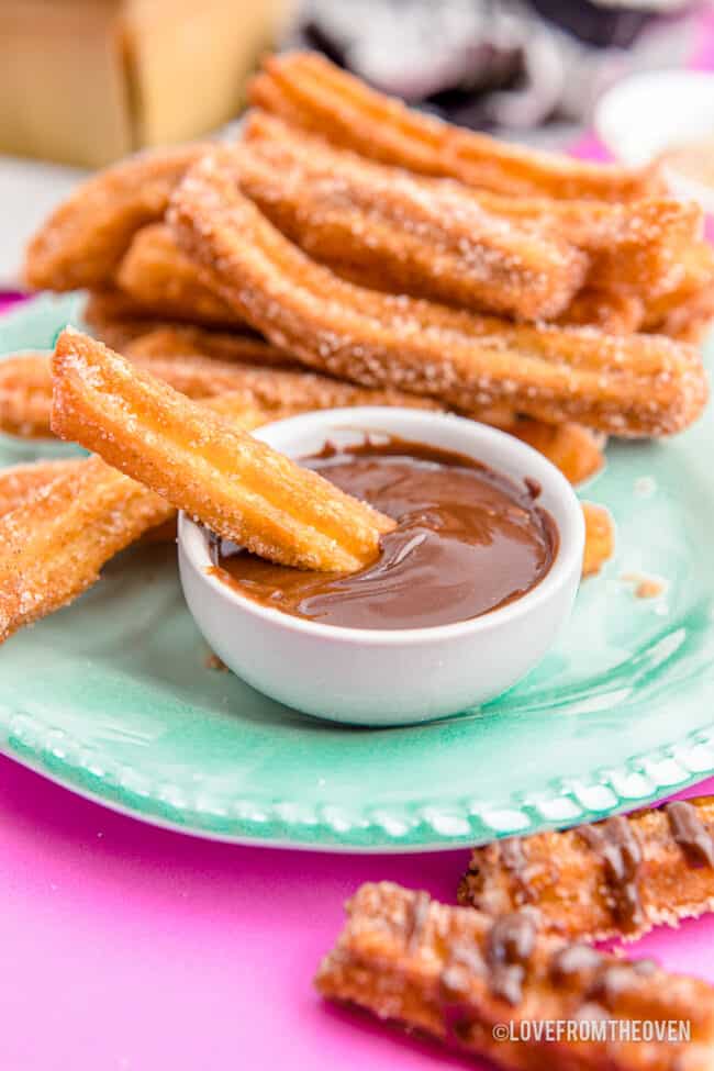 A plate of churros with chocolate sauce.