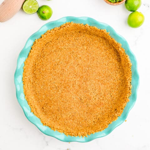 A graham cracker crust in a blue pie pan.