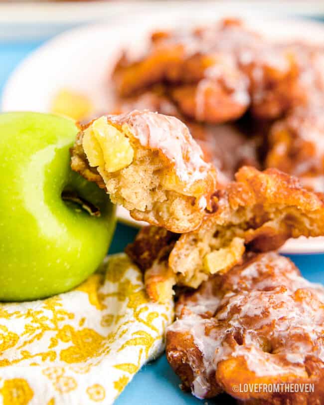 An apple fritter next to an apple.