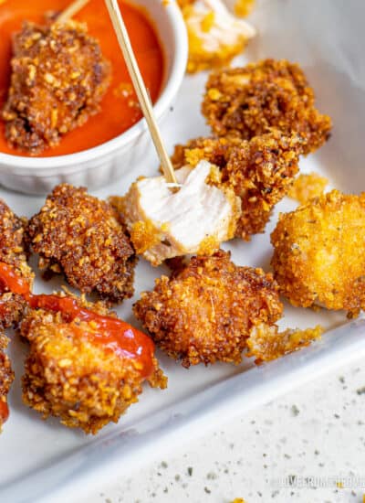 Popcorn chicken next to a dipping sauce.