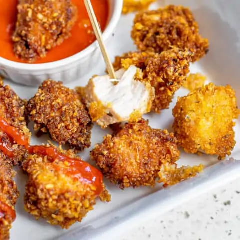 Popcorn chicken next to a dipping sauce.