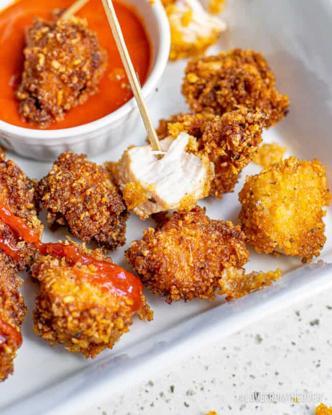 Popcorn chicken next to a dipping sauce.