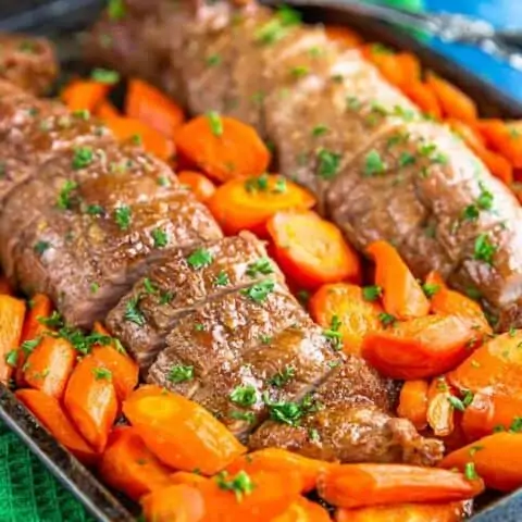 A close up of pork tenderloin with carrots.