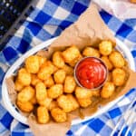 A basket of air fryer tater tots on a blue and white background.