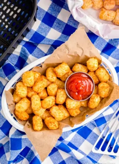 A basket of air fryer tater tots on a blue and white background.