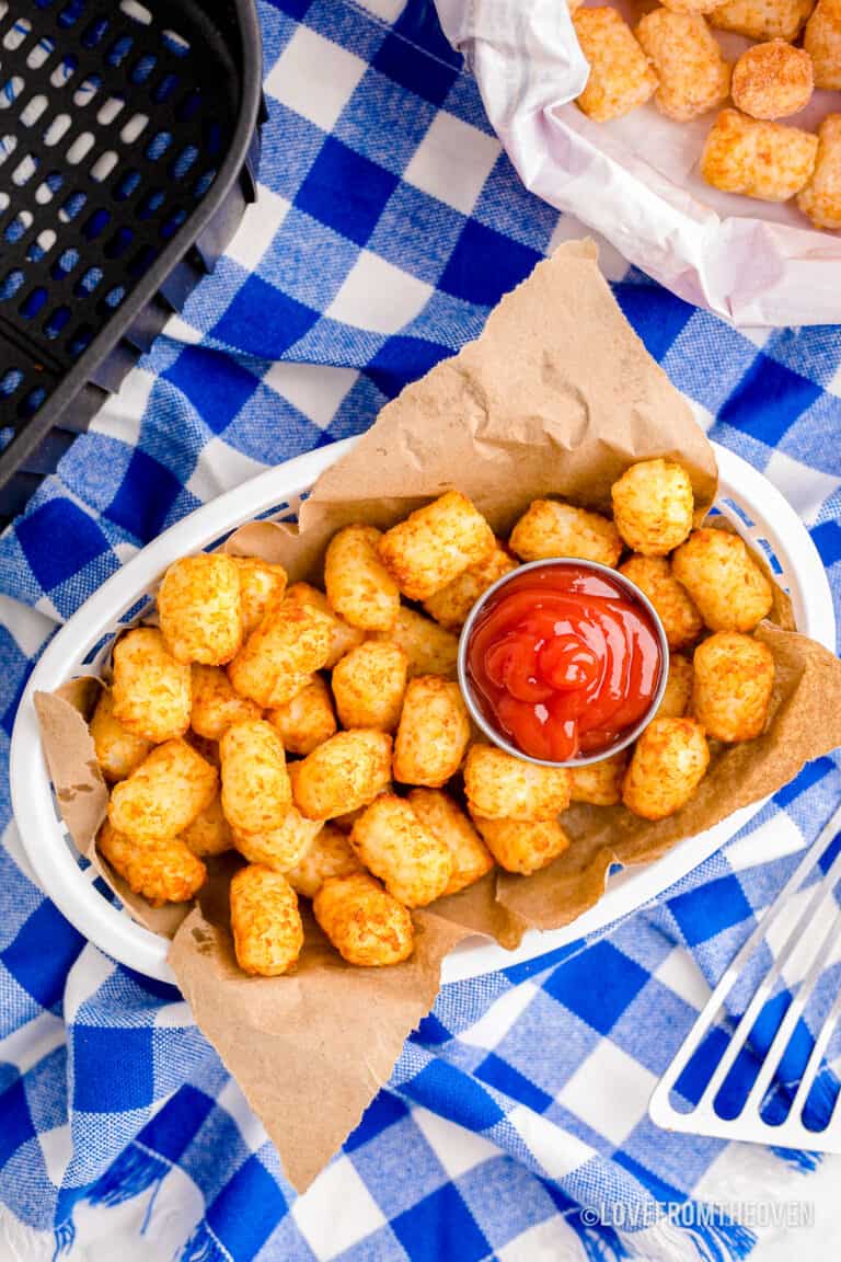 A basket of air fryer tater tots on a blue and white background.