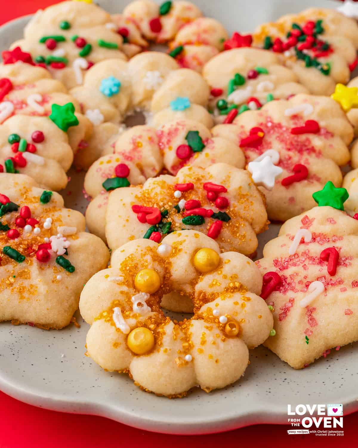 Spritz Cookies shaped like wreaths decorated with sprinkles.