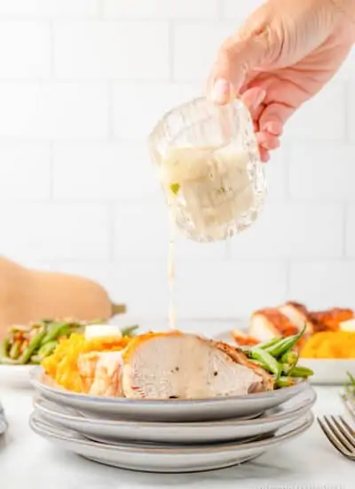 turkey gravy being poured over a plate of turkey and sides