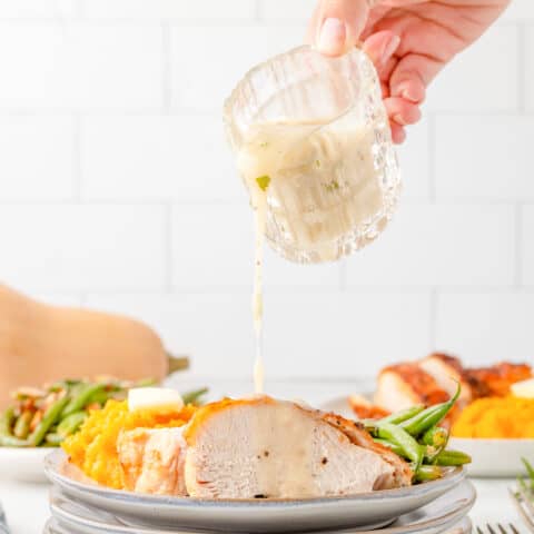 turkey gravy being poured over a plate of turkey and sides