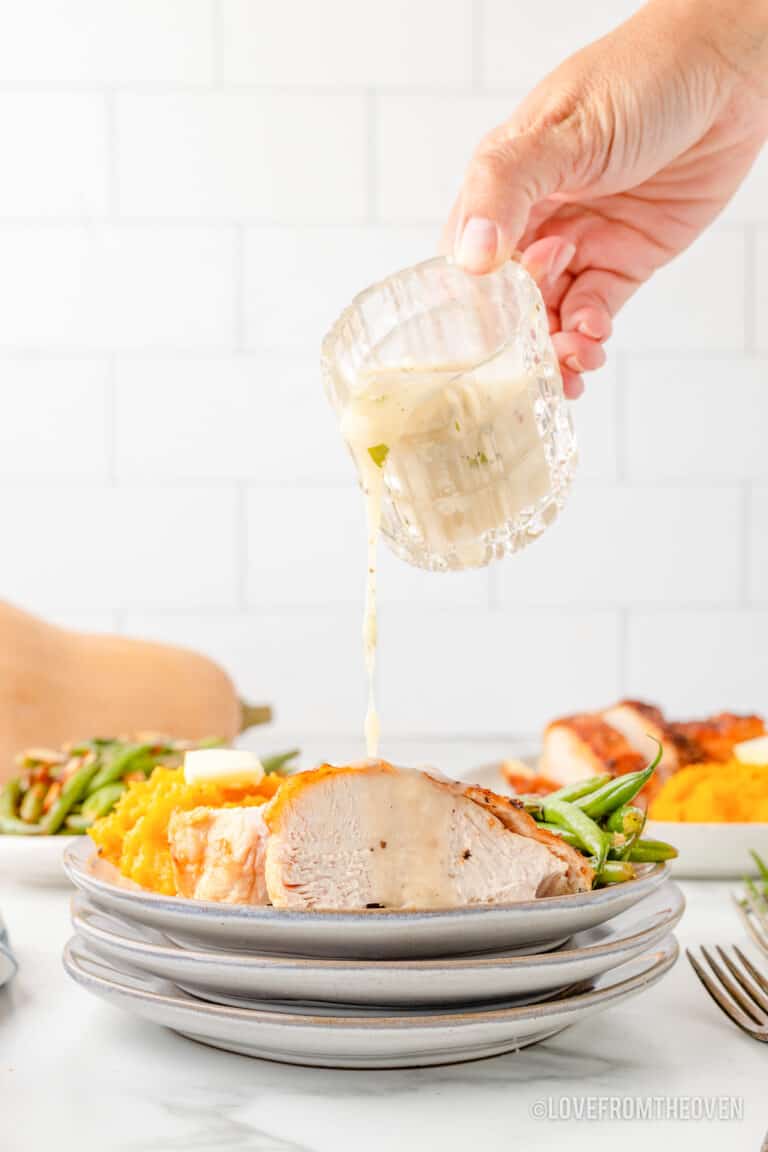 turkey gravy being poured over a plate of turkey and sides