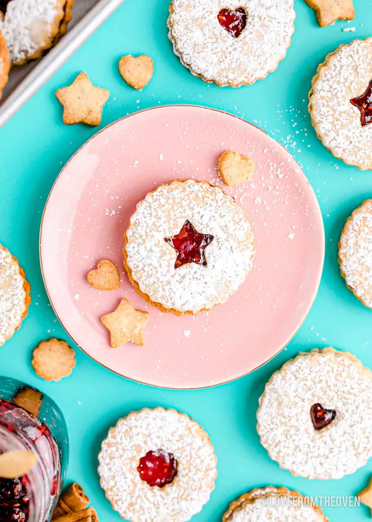 Linzer cookies on a pink plate and blue background.