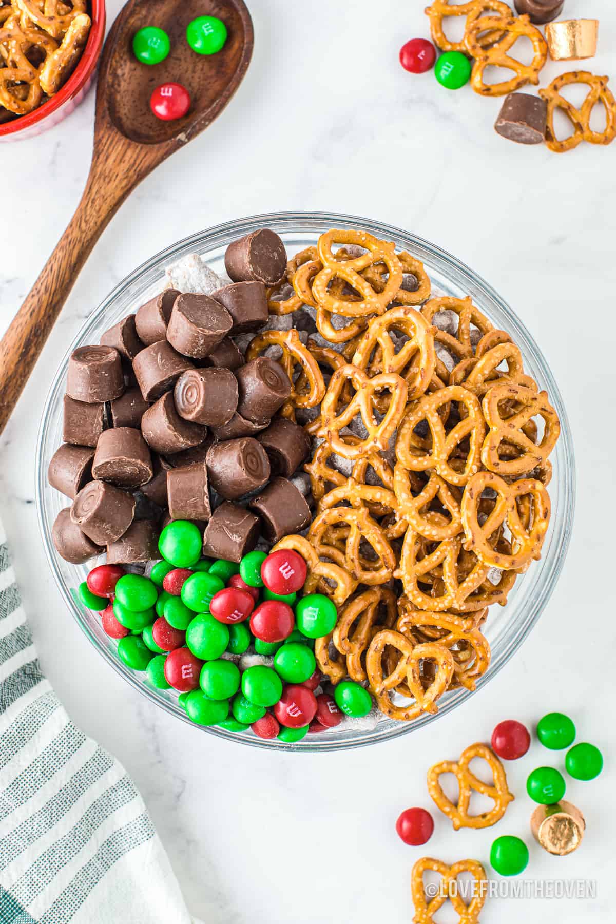 A close up of m&ms rolos and pretzels in a bowl.