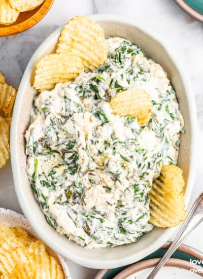 A white bowl of crockpot spinach artichoke dip.