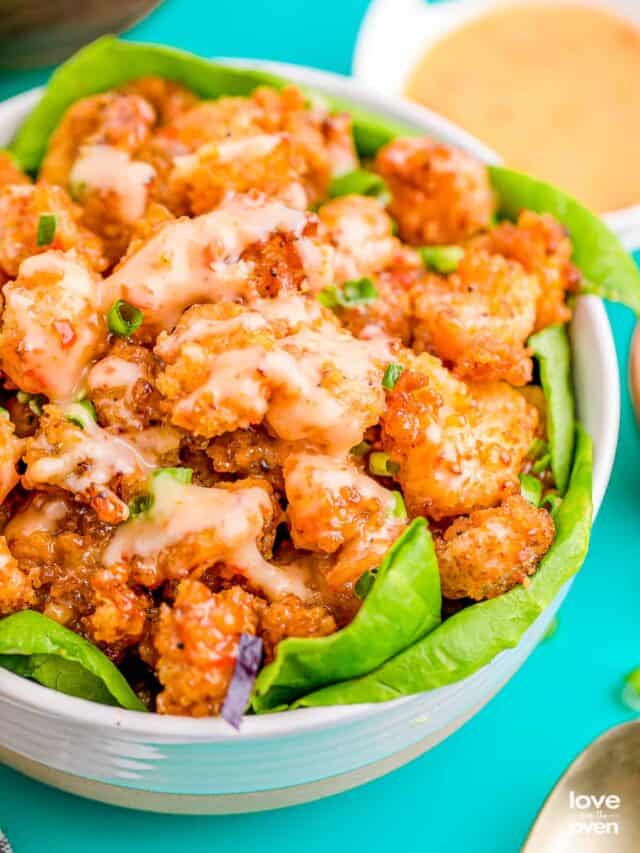 A bowl of bang bang shrimp on a blue background.